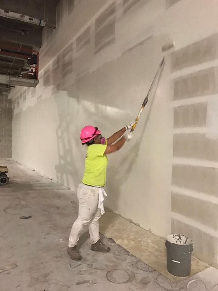 Commercial painter applying coating on large wall