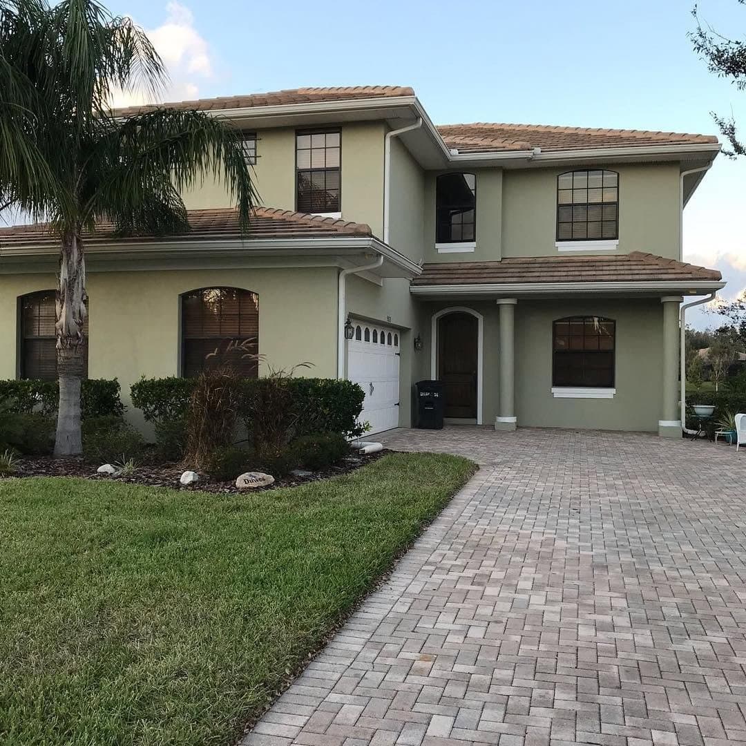 Green exterior home painting with paver driveway